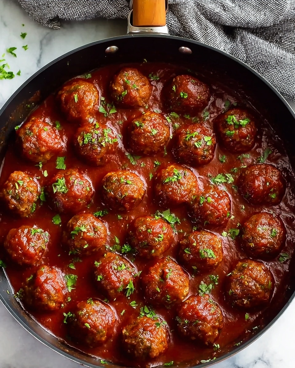 The image shows several glazed meatballs covered in a shiny, thick reddish-brown sauce, sprinkled with small green herb pieces on top. One meatball is held by a wooden spoon, revealing a slightly textured surface with bits of meat visible through the glossy sauce. The meatballs are round and cooked evenly in size and color. They sit closely together with the sauce pooling around them and more green herb bits scattered over. The background has a white marbled texture. photo taken with an iphone --ar 4:5 --v 7