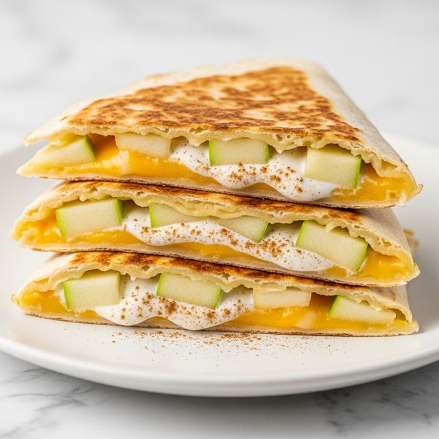 The image shows a white plate with three folded quesadilla slices stacked on top of each other on a white marbled texture. Each quesadilla has a golden-brown grilled tortilla exterior. Inside, visible layers include a melted yellow cheese, chunks of light green apple, and a creamy white filling, possibly yogurt or cream, sprinkled with light brown cinnamon. The quesadilla edges look soft but well cooked, with a slight crisp. The whole setup is neat and close-up, with soft light highlighting the textures. Photo taken with an iphone --ar 4:5 --v 7
