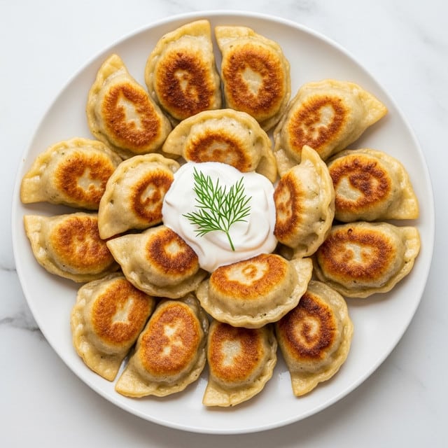 The image shows a white plate filled with small golden brown fried dumplings, arranged in a slightly overlapping way. On top of the dumplings is a dollop of white sour cream with a sprig of green dill placed in the center. The dumplings have a slightly crispy texture with some darker spots from frying, and the filling inside hints at a light, soft texture. The plate is set on a white marbled surface, giving a clean and bright look to the scene. Photo taken with an iphone --ar 4:5 --v 7