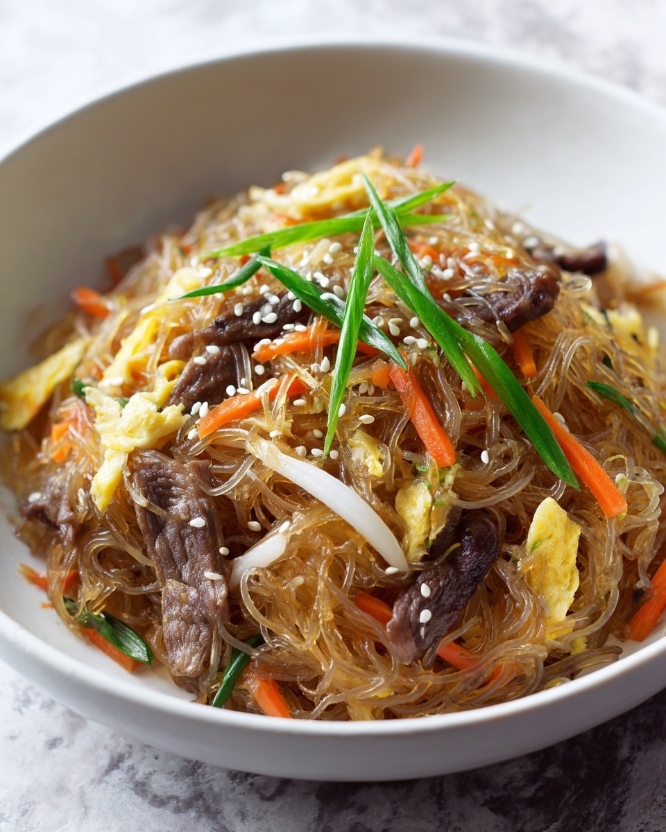 A close-up view of a white bowl filled with translucent, slightly brown glass noodles mixed with thin strips of light yellow egg, orange carrot sticks, dark brown mushroom slices, thinly sliced cooked beef pieces, and white onion slices. The dish is also decorated with small white sesame seeds sprinkled evenly and a few green onion stalks placed on top, all set against a white marbled texture background. photo taken with an iphone --ar 4:5 --v 7