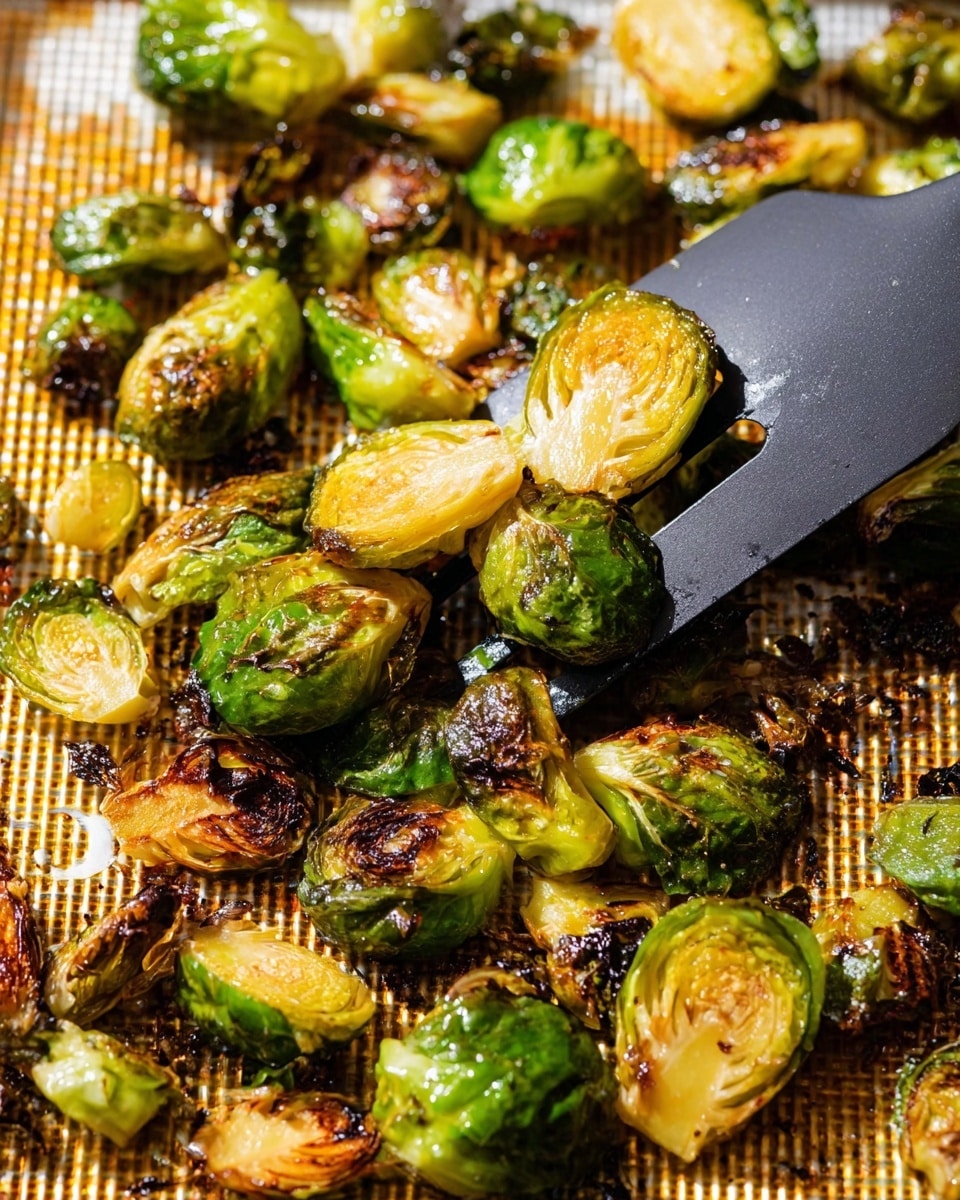Close-up of roasted Brussels sprouts with a mix of green and golden brown colors from caramelization, showing crispy, charred edges and tender interiors. The Brussels sprouts are cut mostly in halves with some whole, laid on a textured metal pan with a warm brown hue. A black spatula lifts some of the sprouts on the right side, highlighting the contrast between the bright green layers and the deep browned grilled marks. The image is brightly lit, emphasizing the shiny, oily surface and crispy textures of the vegetables on a white marbled background. photo taken with an iphone --ar 4:5 --v 7