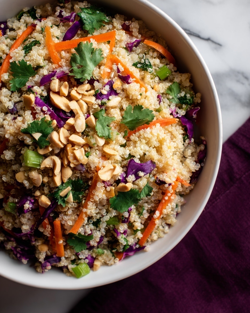 A close-up view of a white bowl filled with a colorful quinoa salad. The base layer is fluffy white quinoa with a slightly translucent texture. Mixed throughout are thin orange carrot sticks and small pieces of bright green celery, adding texture and fresh color. There are also small chunks of purple cabbage scattered across the salad, giving a vibrant contrast. On top, chopped peanuts are sprinkled generously along with fresh, dark green cilantro leaves, adding a fresh and crunchy look. The bowl is placed on a white marbled surface with a dark purple cloth partially visible underneath. photo taken with an iphone --ar 4:5 --v 7